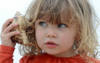 kind aandachtig luisterend in schelp