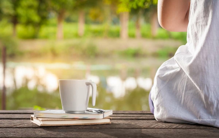 rust uitstralende foto van meisje op houten steiger met boeken en kop koffie of thee uitkijkend op een water